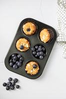 White old wall with cracks printed on vinyl backdrop for food photography. Flat lay picture of blueberry muffins in old tin with kitchen cloth 