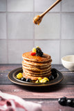 Pancakes shot on a vinyl photography backdrop decorates with fruit, plate and tiled backdrop